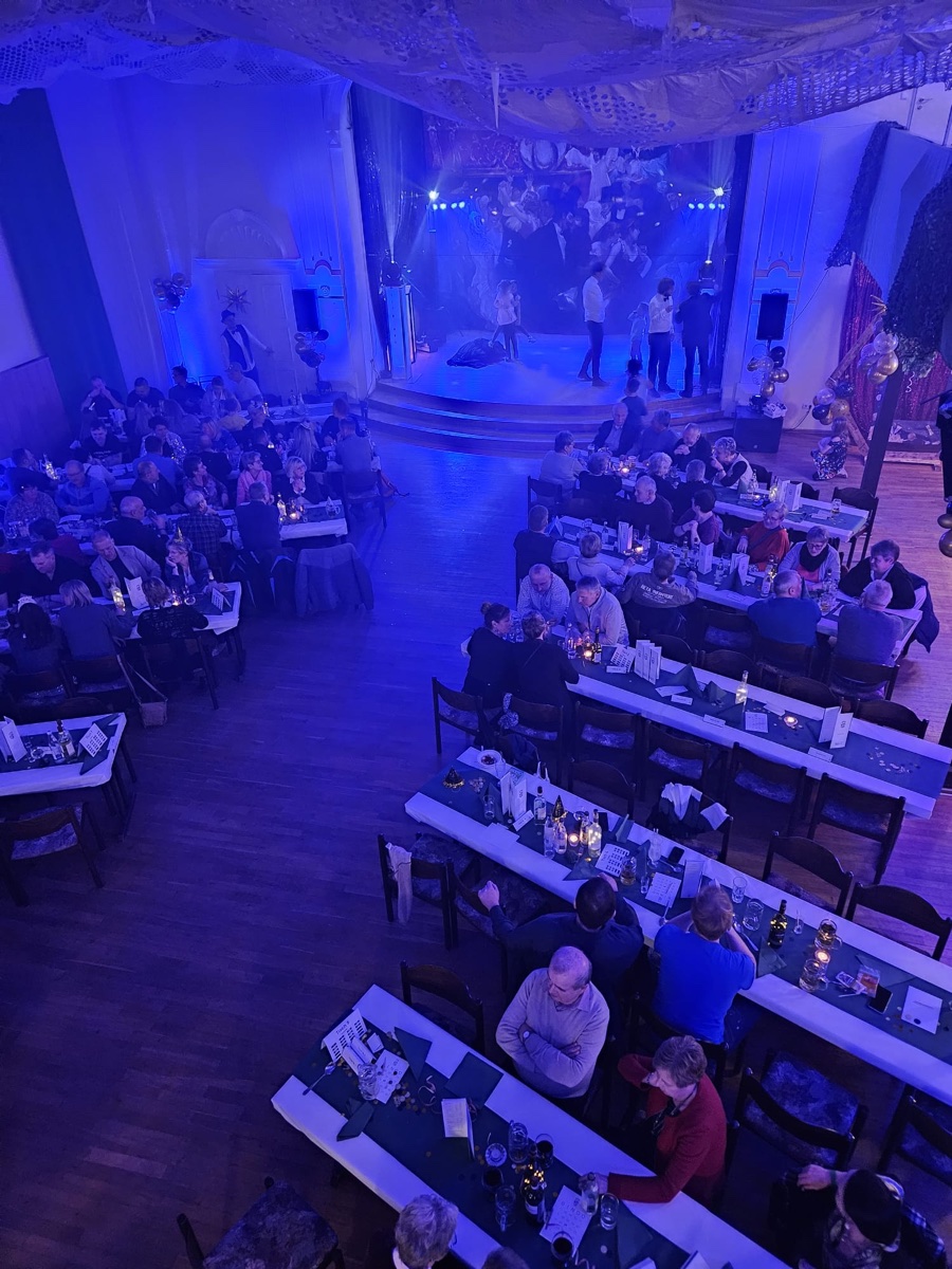 Blick von der Galerie auf den gefüllten, blau beleuchteten Festsaal